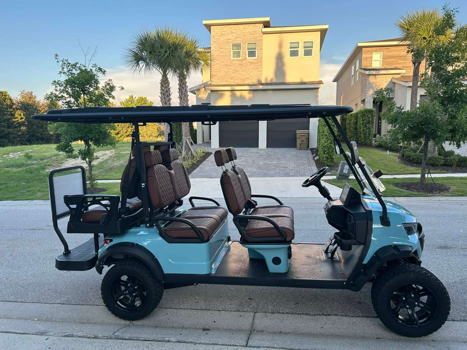 Teal 6-seater lifted golf cart with brown quilted seats parked at a Reunion Resort vacation home