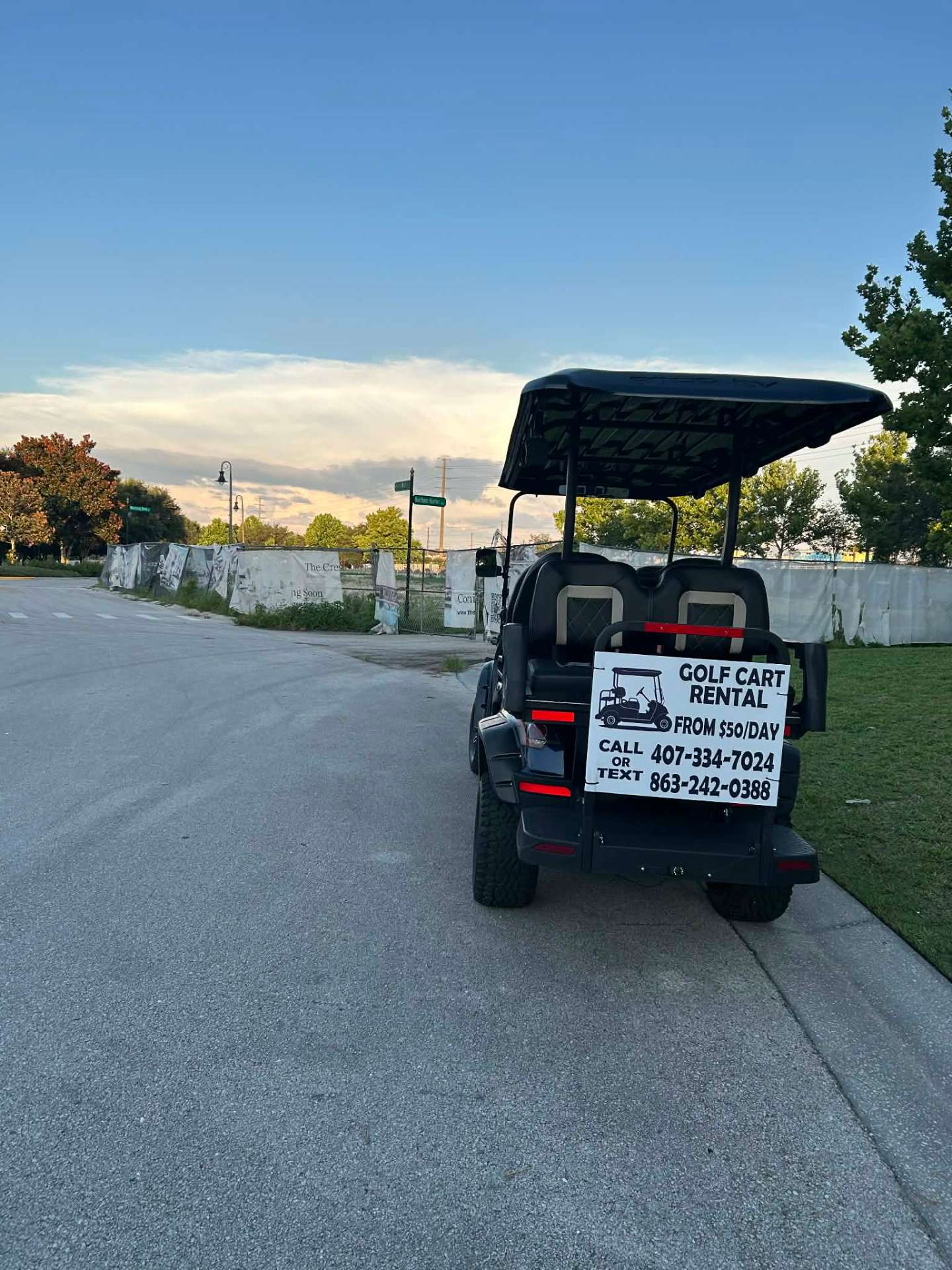 Rear view of black lifted golf cart with Golf Cart Rental $50/day call or text sign at sunset