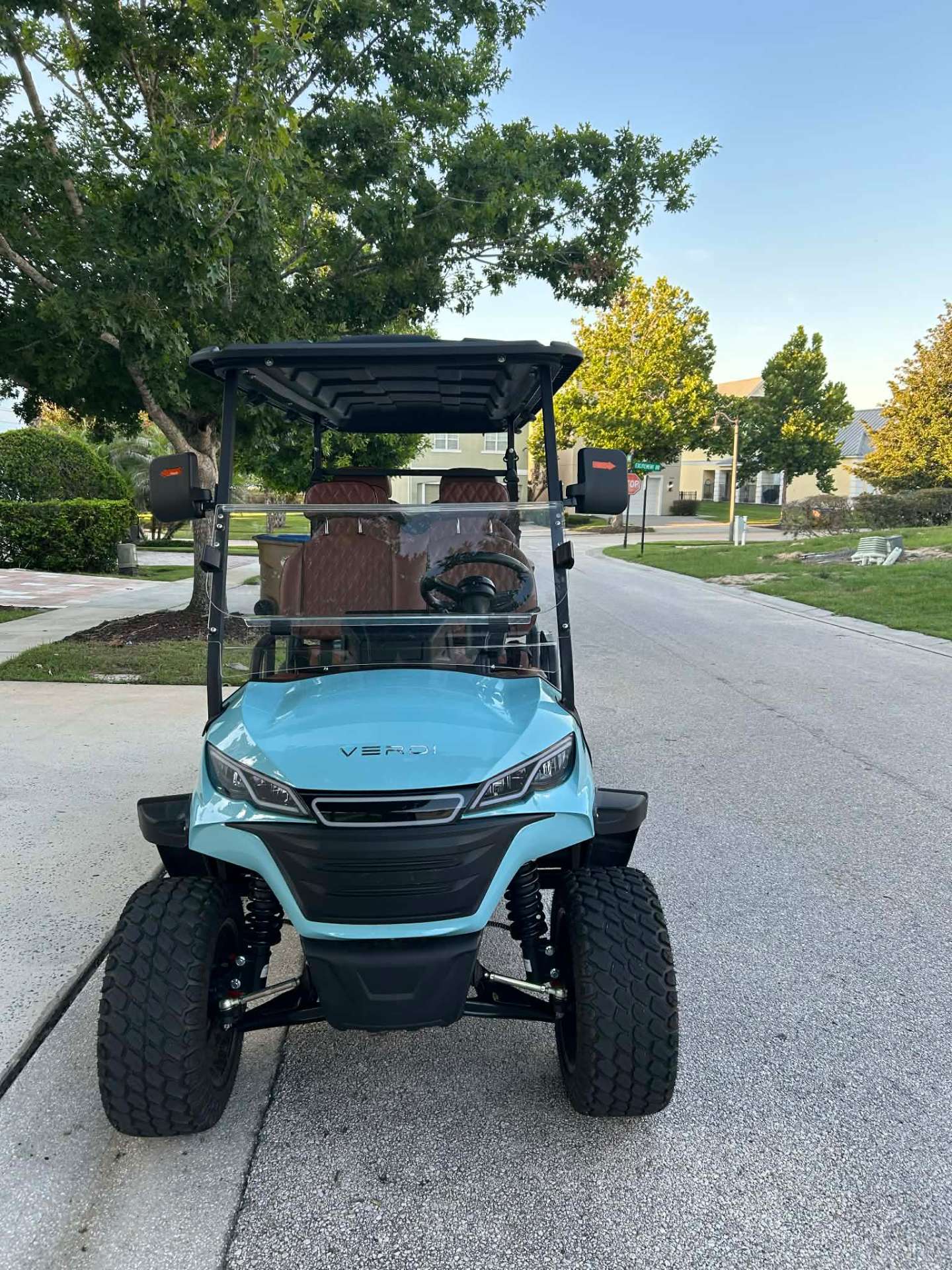 Front view of teal Verdi lifted golf cart parked on a Reunion Resort street at golden hour