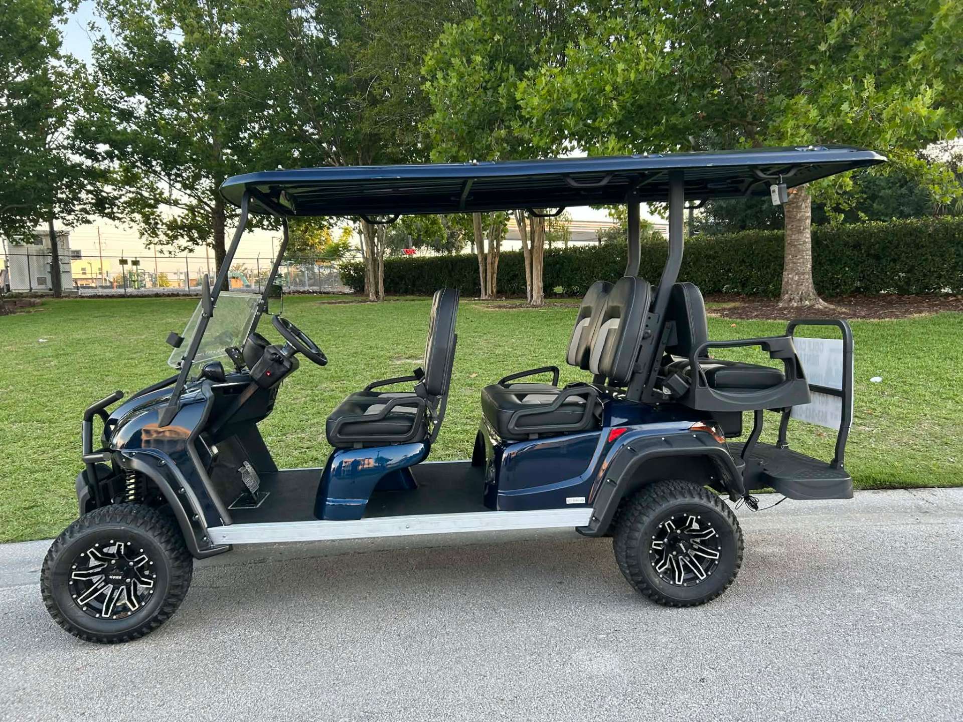Navy blue 6-passenger lifted golf cart rental parked by a park