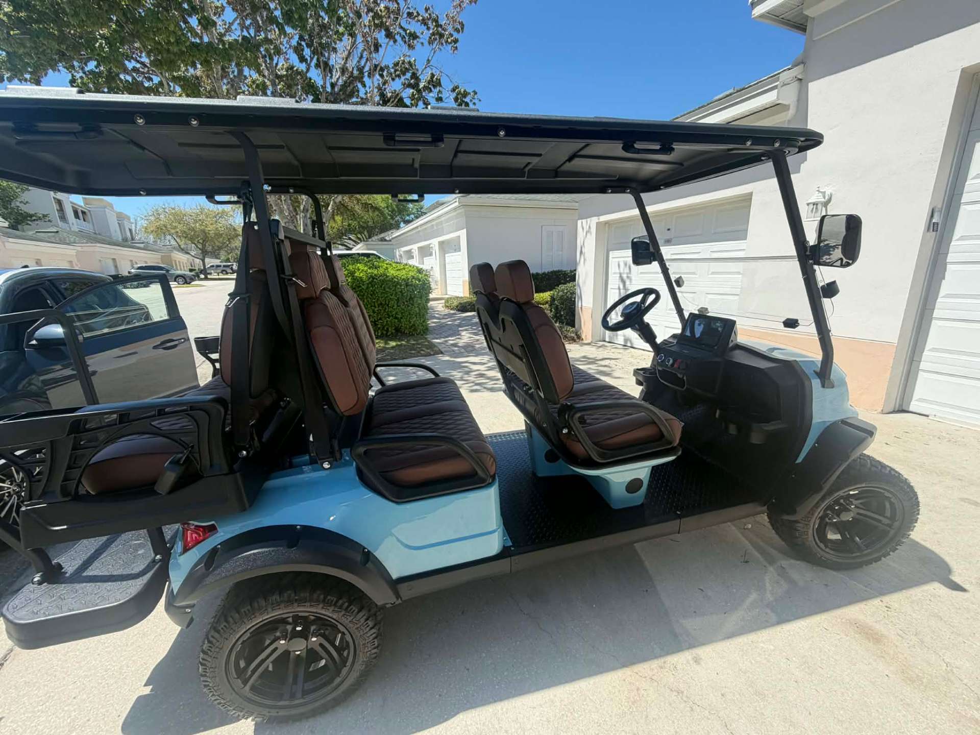 Interior view of teal 6-seater lifted golf cart with brown quilted leather seats